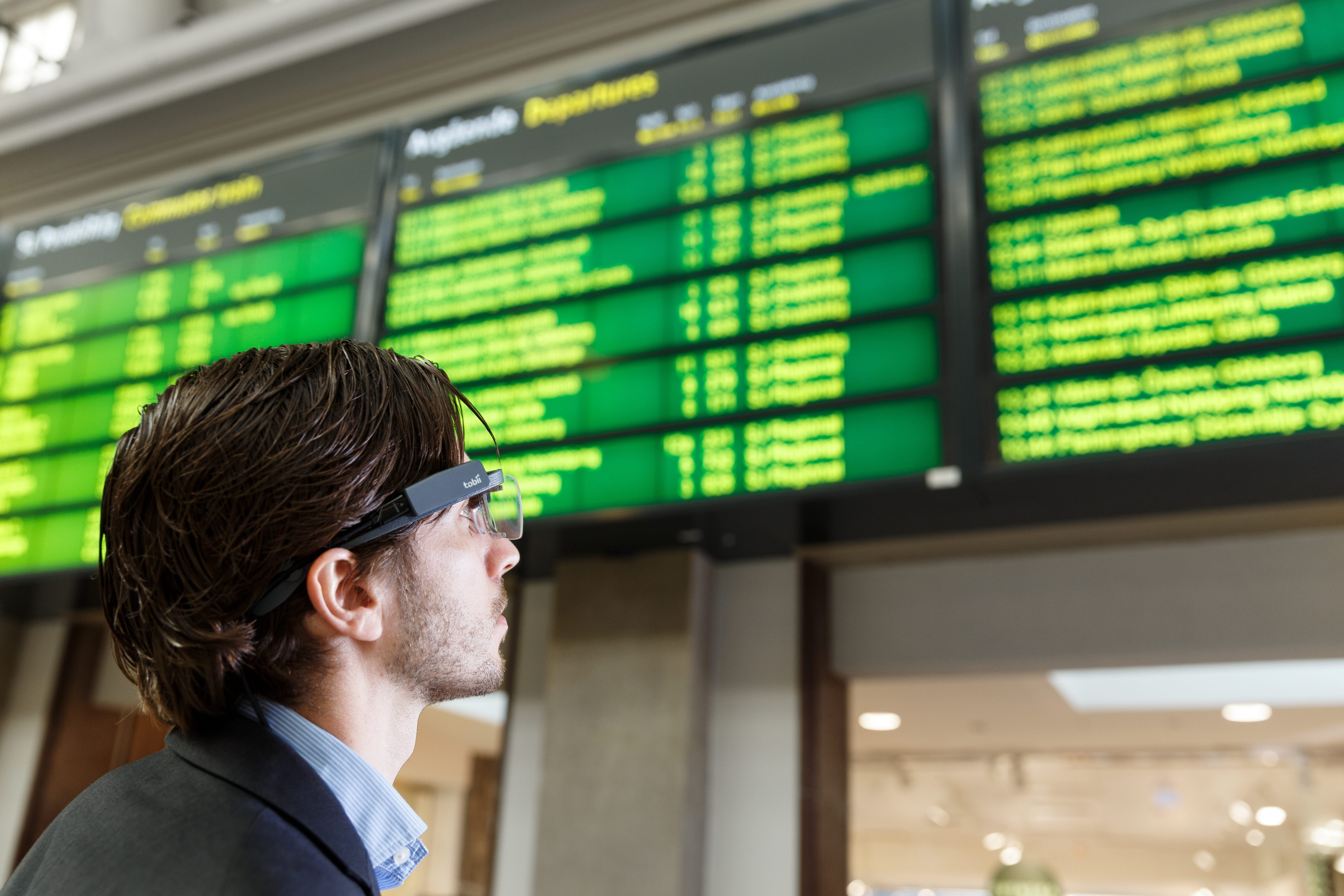 A man wearing Tobii Pro Glasses 2 looks at the timetable display 