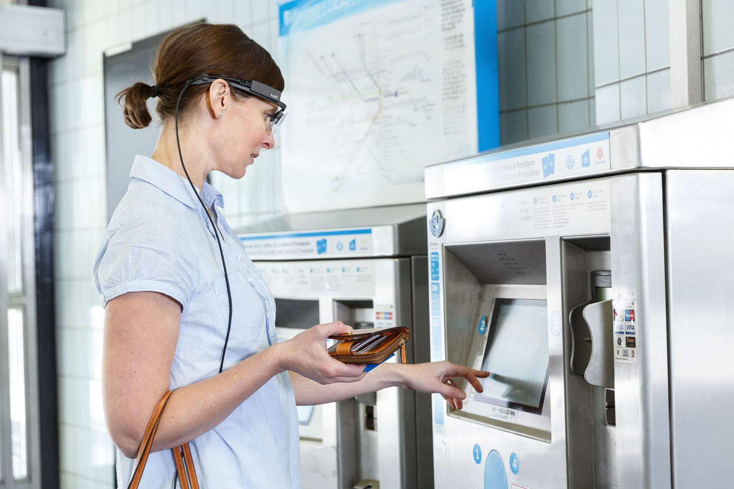 A woman wearing Tobii Pro Glasses 2 buys a ticket from a ticket machine at the train station 